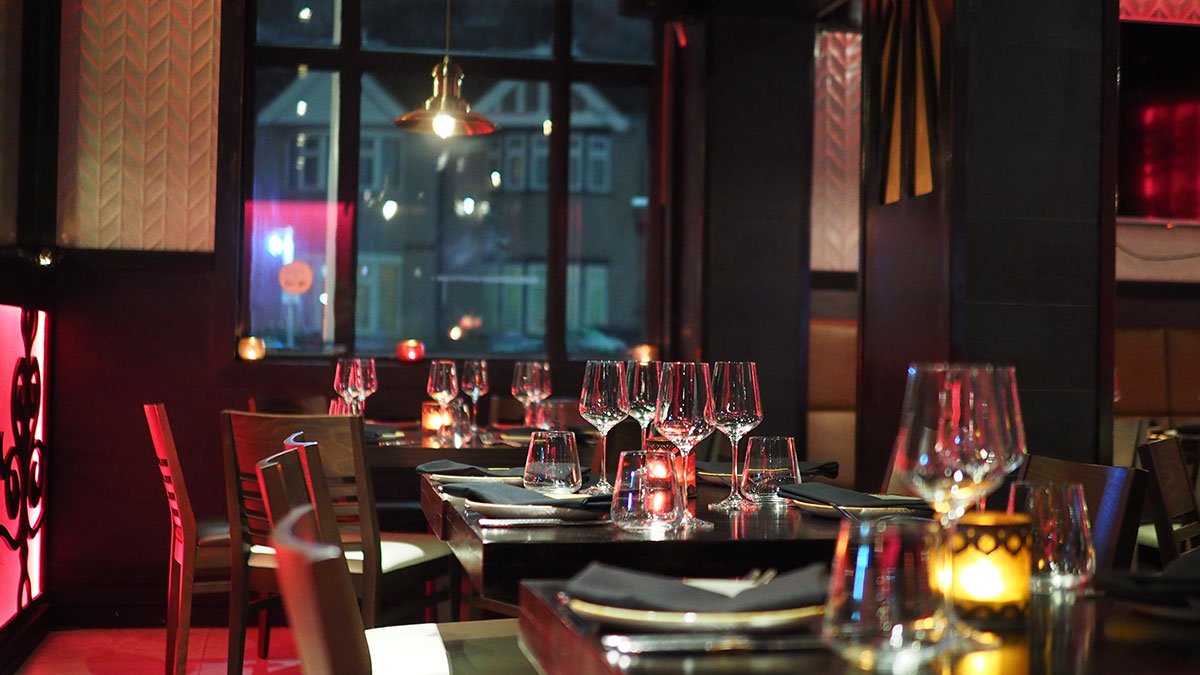 restaurant with chairs and tables stacked with wine glasses having a red ambience and elegance